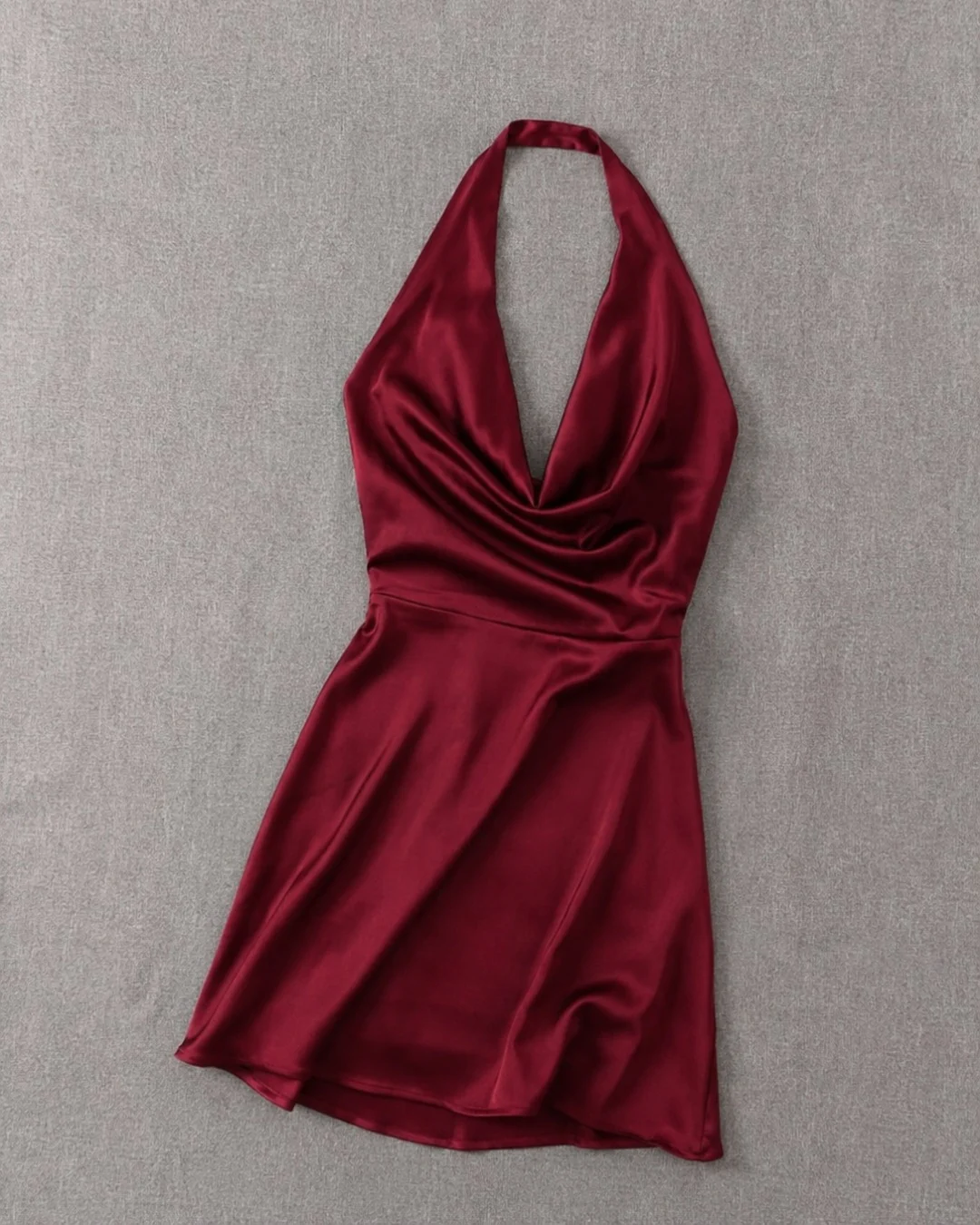 Burgundy satin halter dress photographed as a flat lay