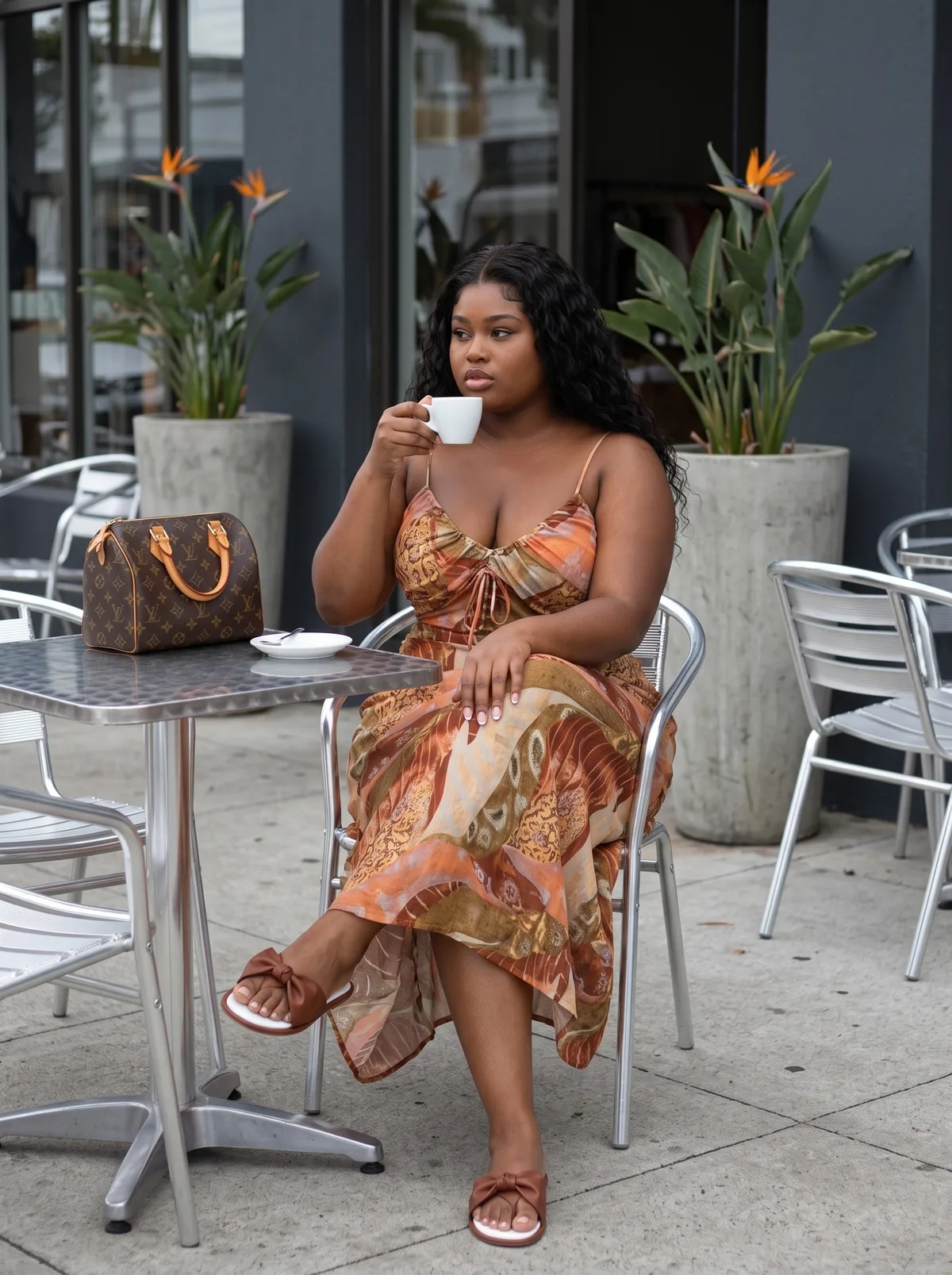 Fictional adult curvy Black woman wearing a patterned dress at an outdoor café